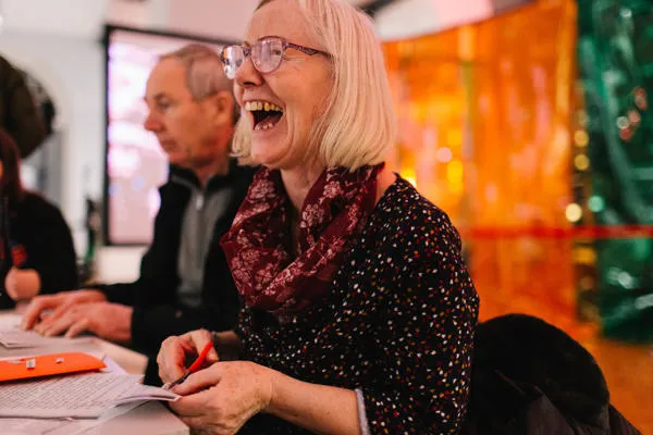 A woman does crafts and smiles.