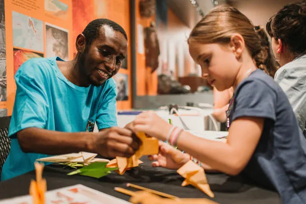 A man helps a girl with crafts.