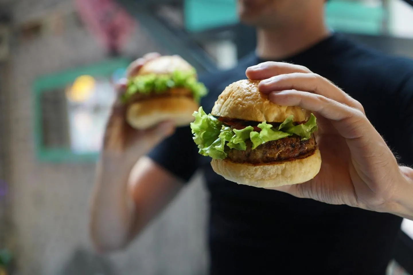 Man holding two burgers, one in each hand.