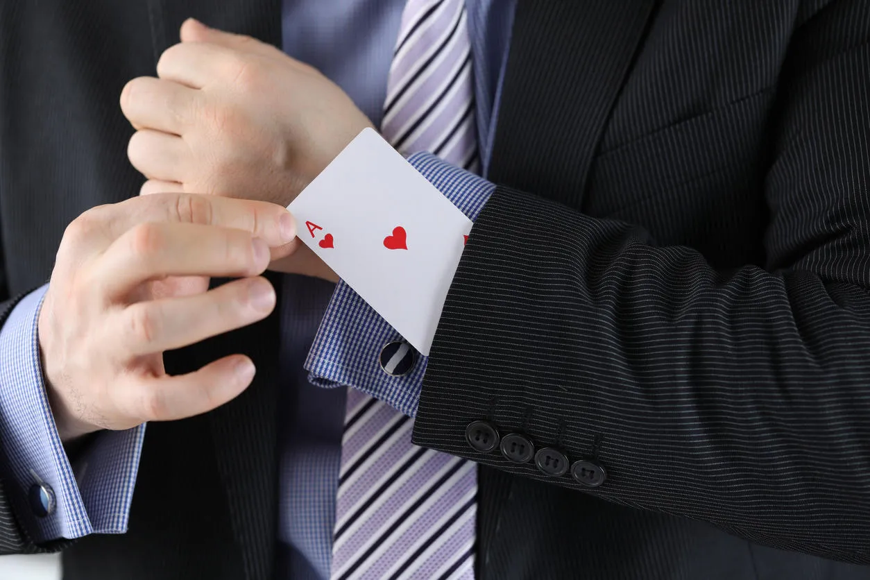 Man in a suit putting an ace up his sleeve