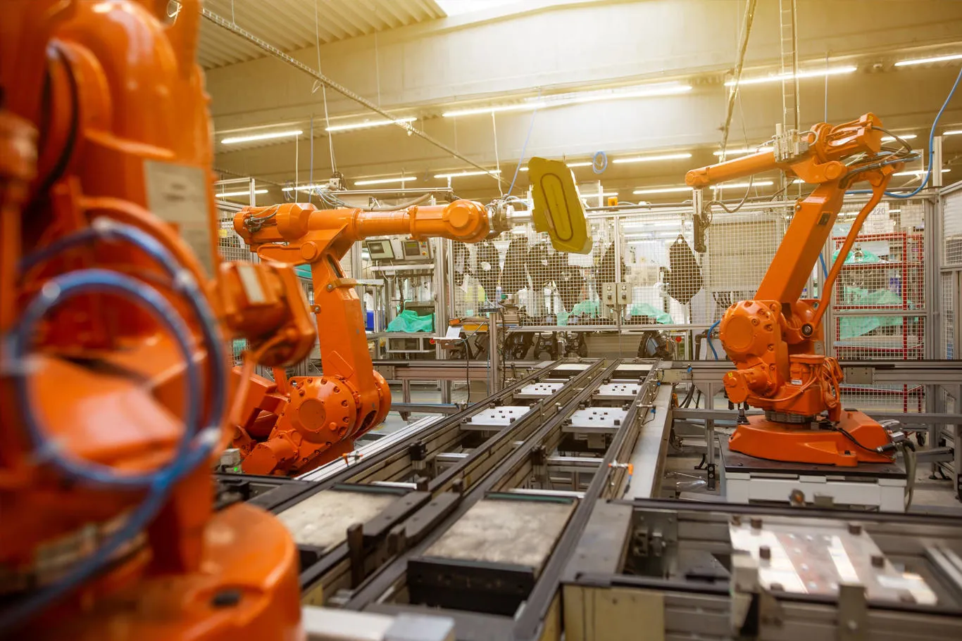 Large, orange-coloured robotic arms on a factory assembly line