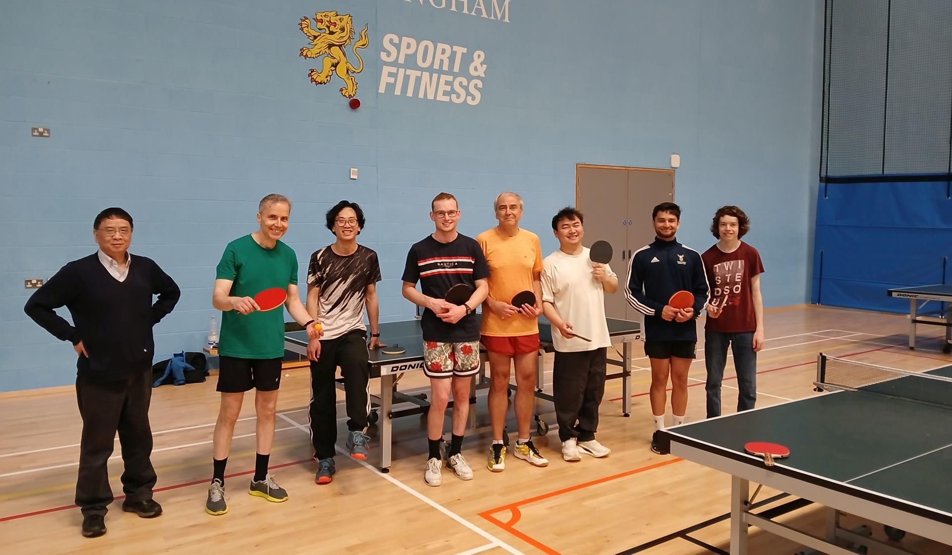 Table tennis players pose in front of University of Birmingham sign in gym