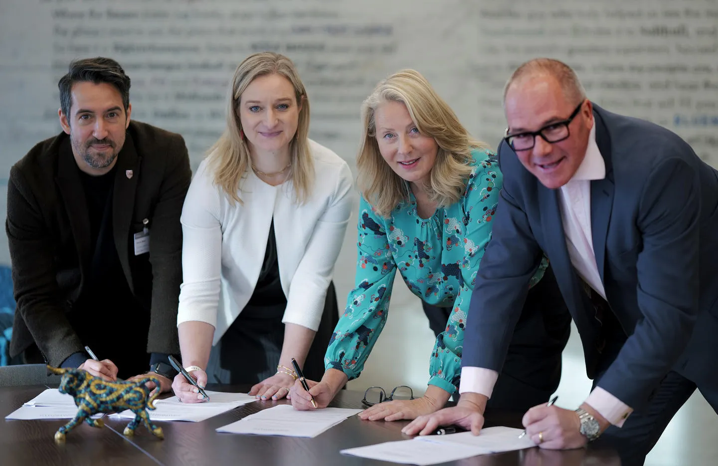 Representatives leaning on table and signing the memorandum. 