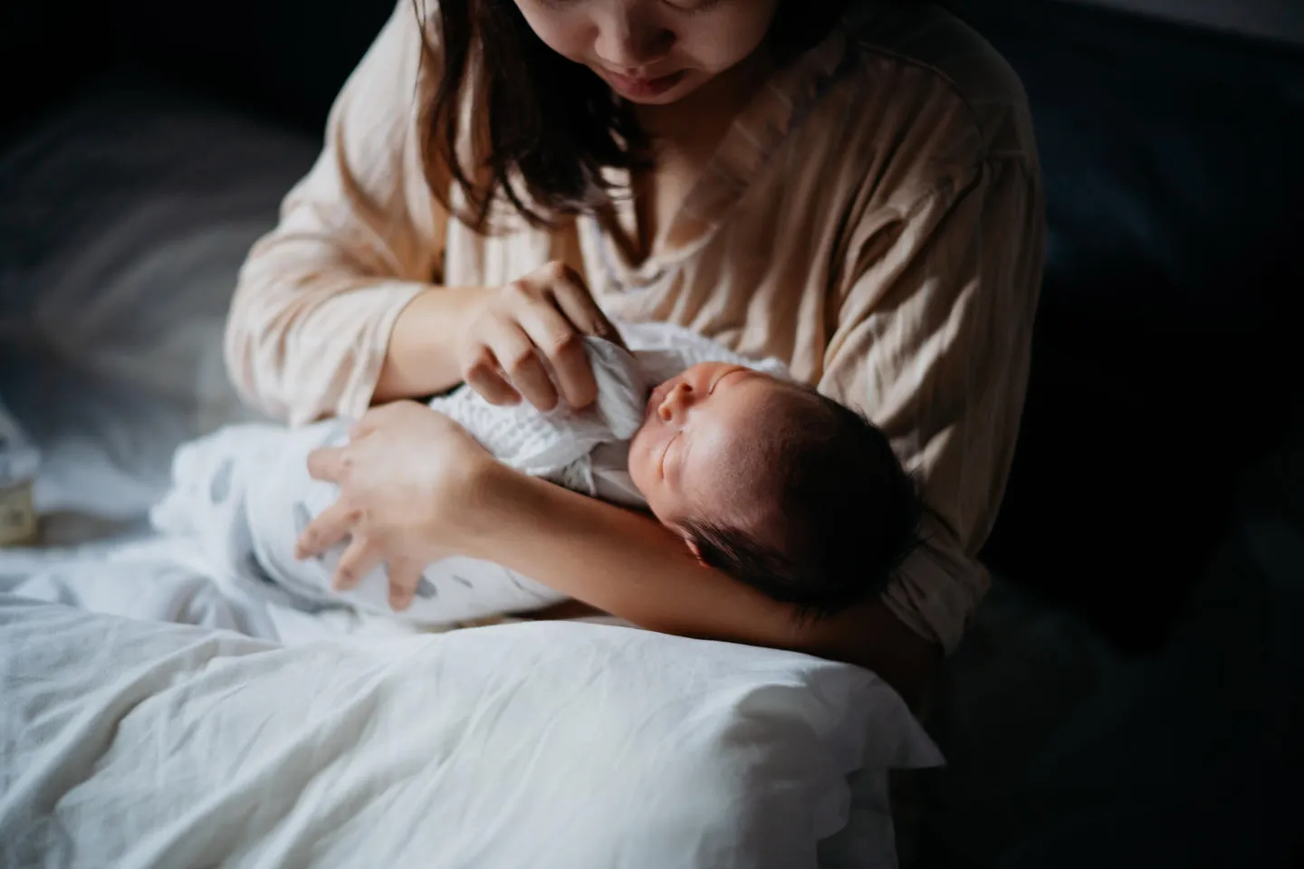 Woman holding baby and dabbing the side of its mouth with a cloth