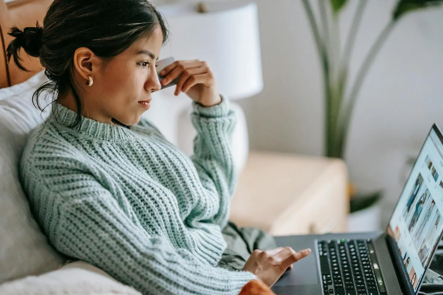 A woman relaxing at home on a sofa with a laptop on her knees