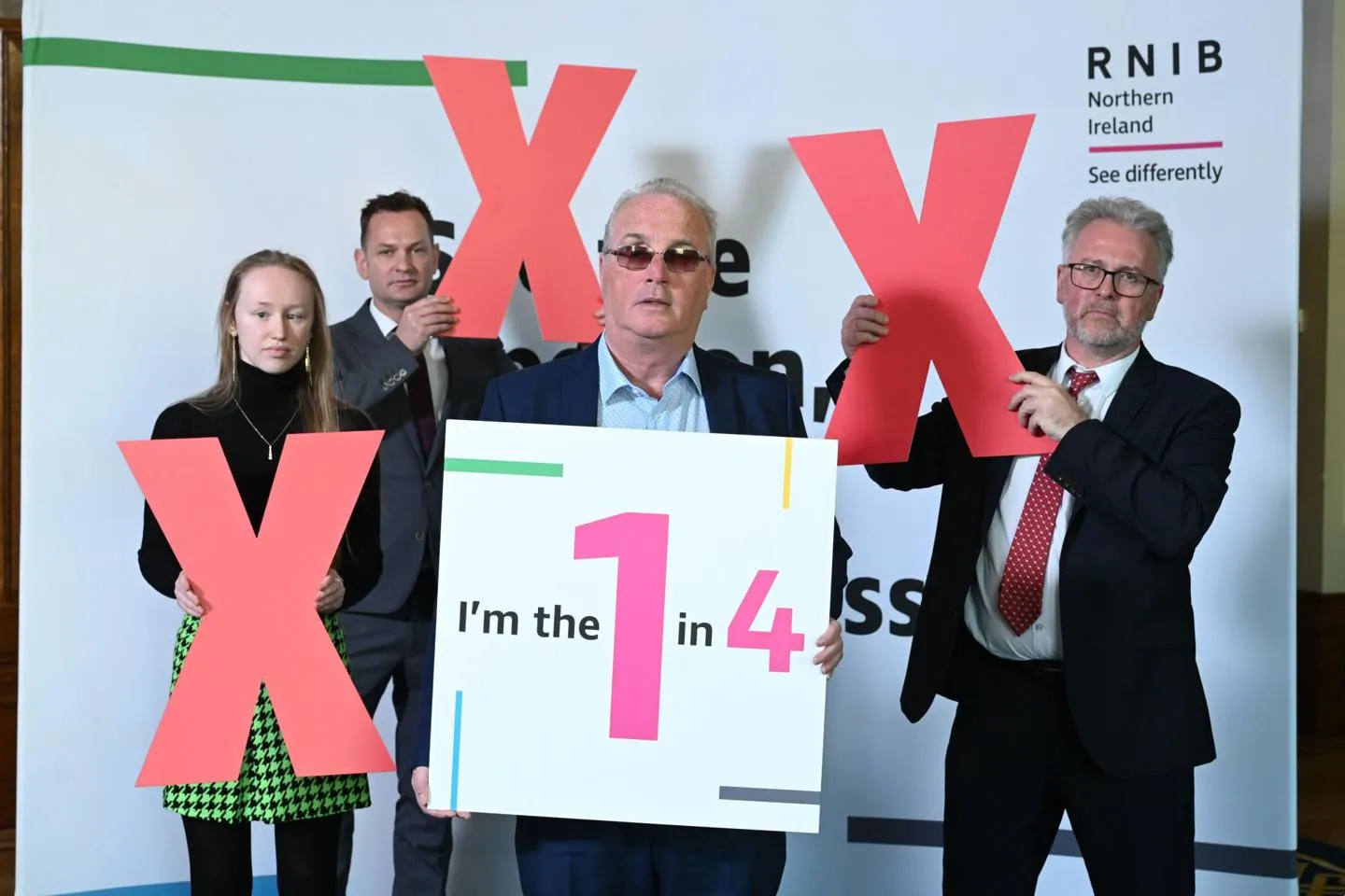 Group of visually impaired people holding red crosses and a poster.