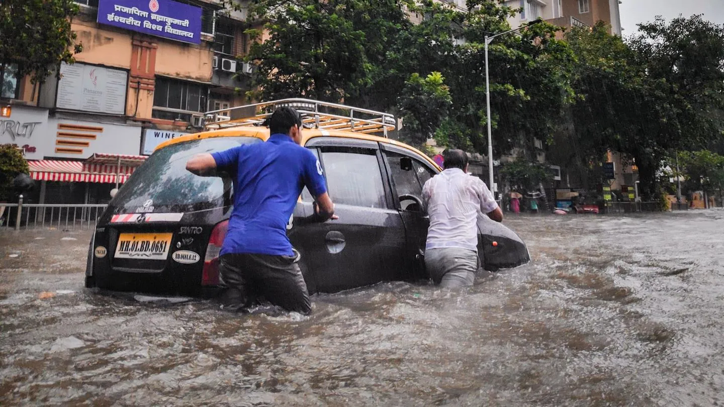Men pushing car through floodwater