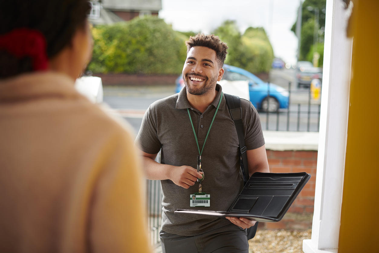 A social landlord rep standing at the open door of a woman's house.