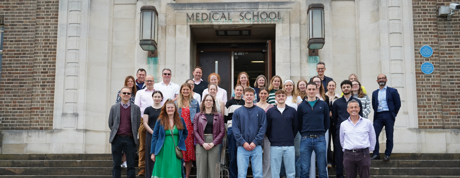 Student winners and staff celebrating the launch of the bursary, stood on the steps of the Medical School