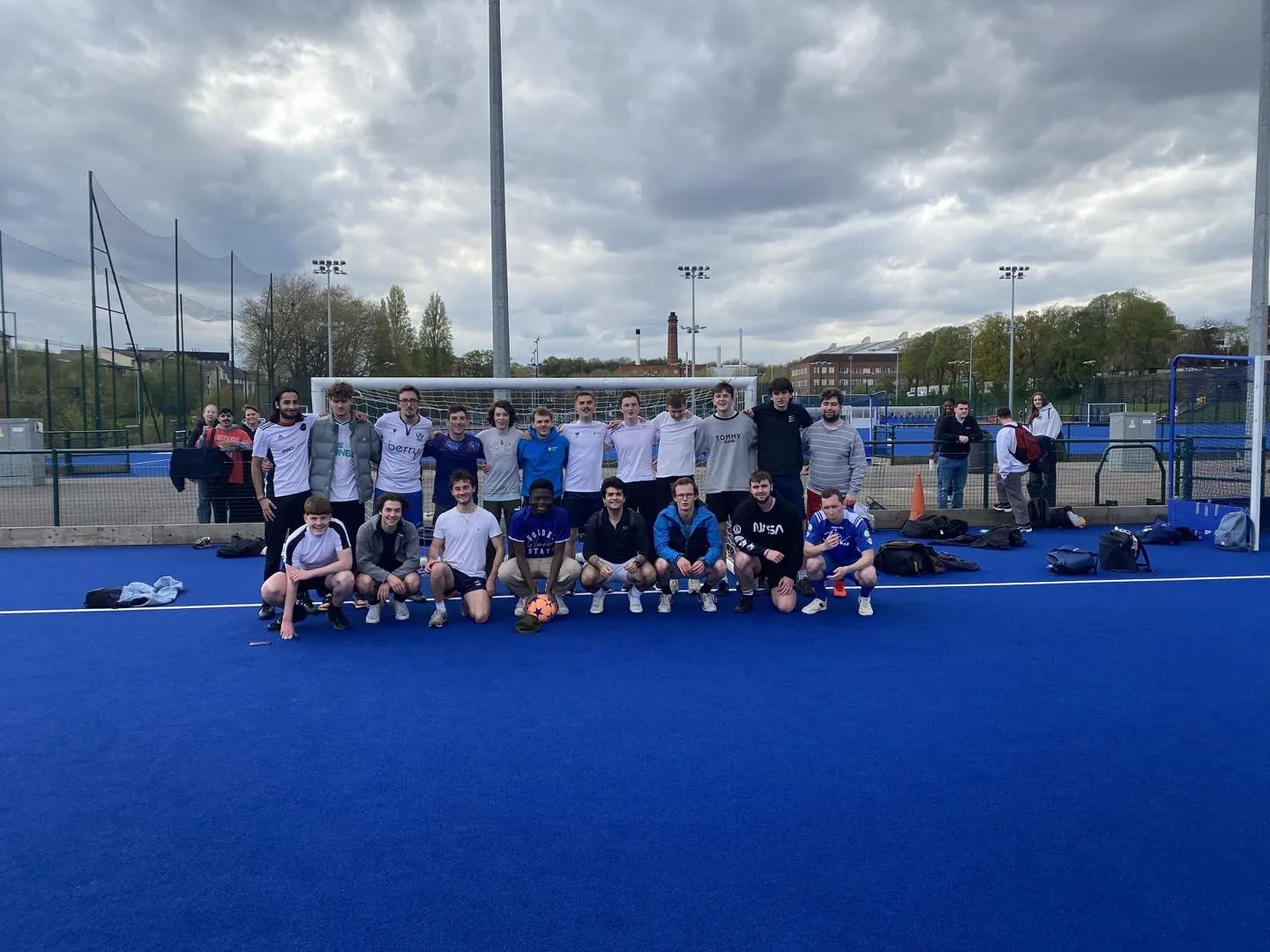 Staff and student squads posing on a football pitch