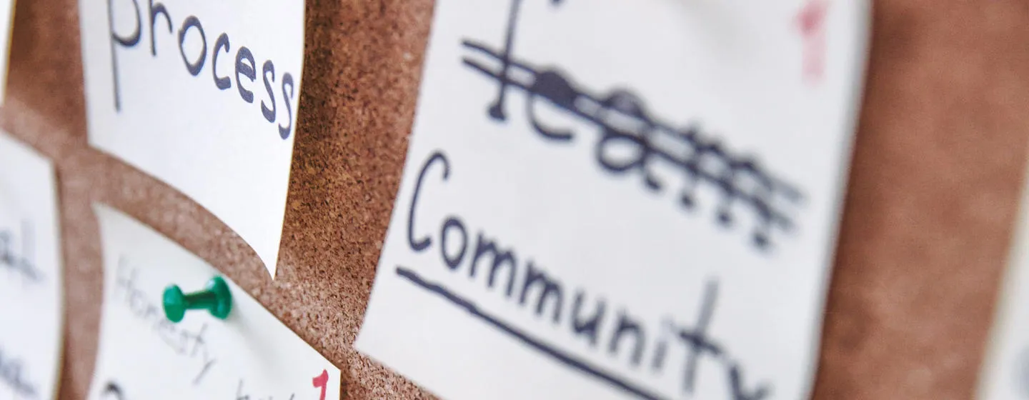 A noticeboard with notes that say 'process' and 'community'