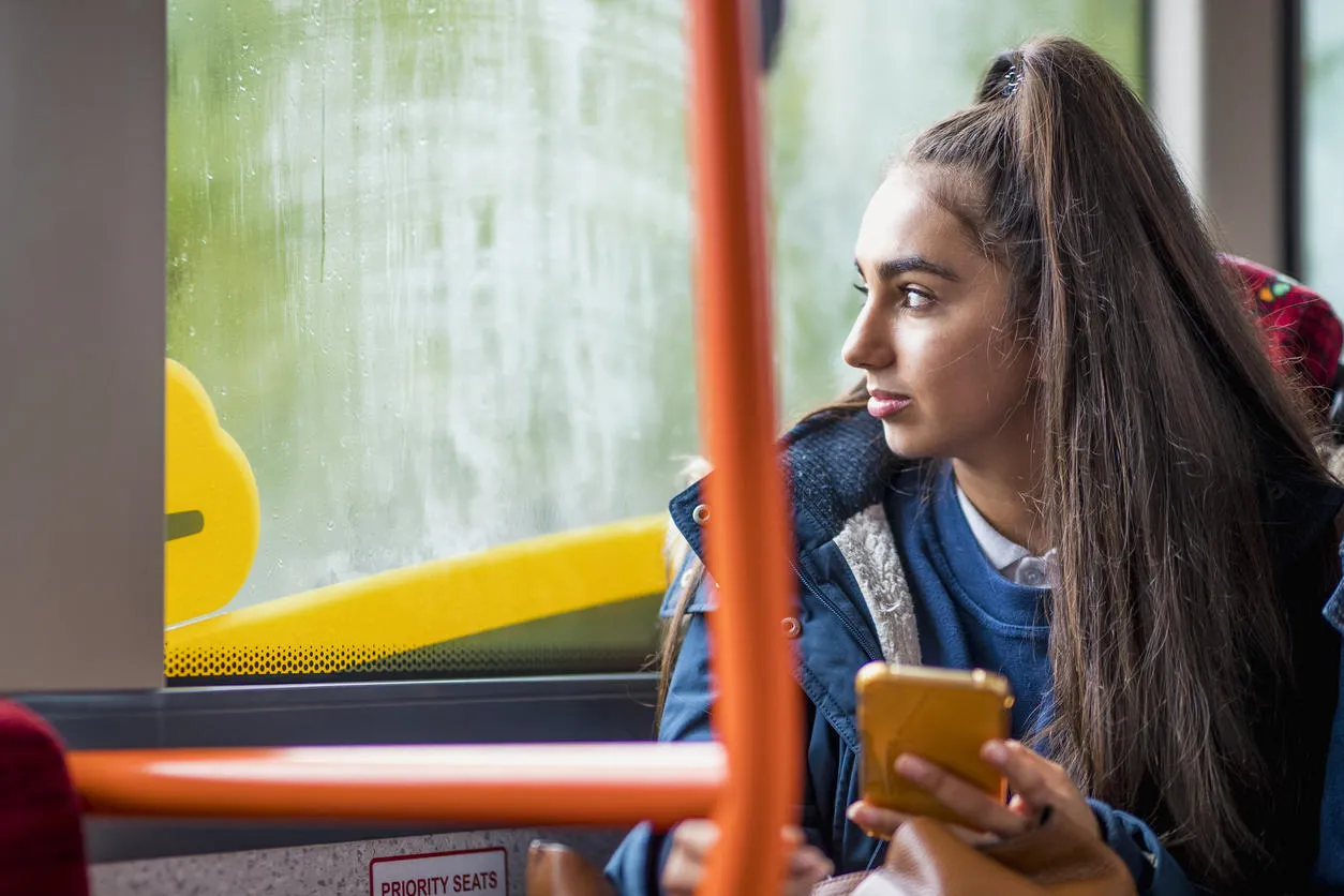 Teenage school girl sitting by herself on the bus.