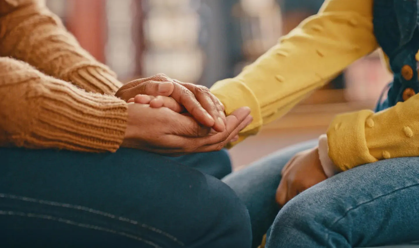 Two people sitting together and holding hands. 