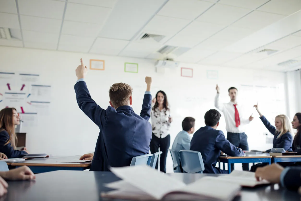 Children raising their hands in a secondary school classroom