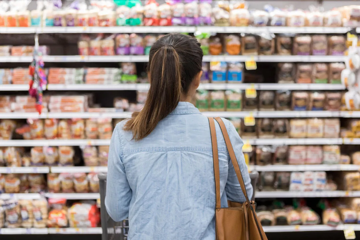 A woman facing supermarket shelves.