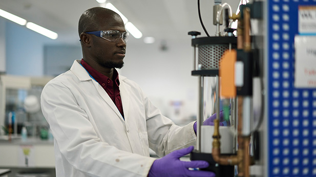 Male student in lab coat operating lab equipment in Birmigham University's Collaborative Teaching Laboratory